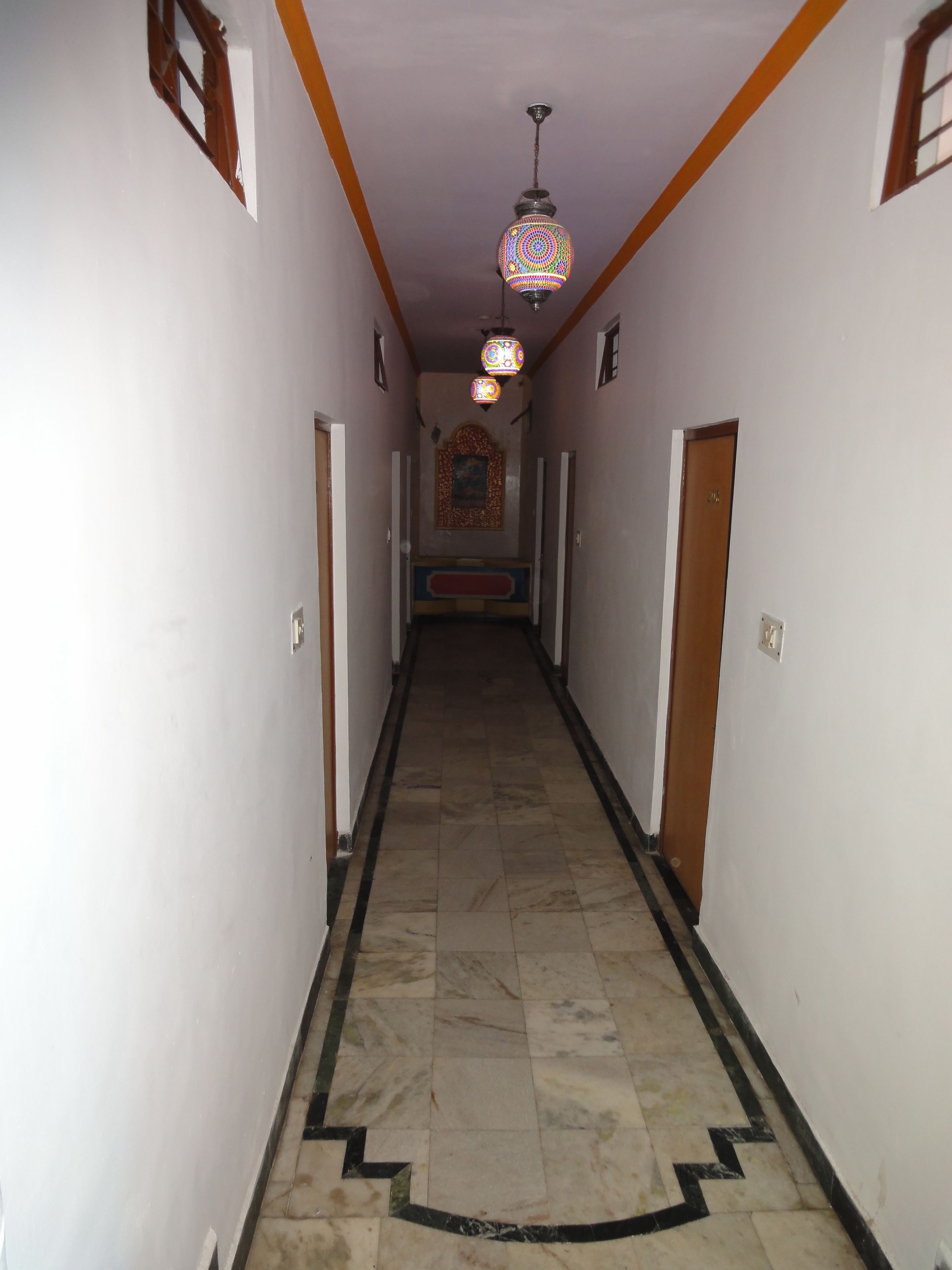 A hallway with patterned floor tiles, a ceiling light fixture, and a door at the end.