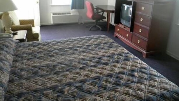 A hotel room with a large bed, a desk with a chair, a television, and a dresser. - USA Inn and Suites Morgantown (Morgantown)