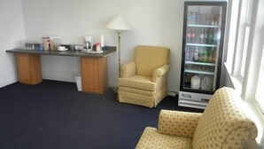 A room with a desk, a chair, a vending machine, and a window. - USA Inn and Suites Morgantown (Morgantown)