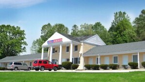 A motel with a single-story structure, a covered front porch, and a parking area with two vehicles. - USA Inn and Suites Morgantown (Morgantown)