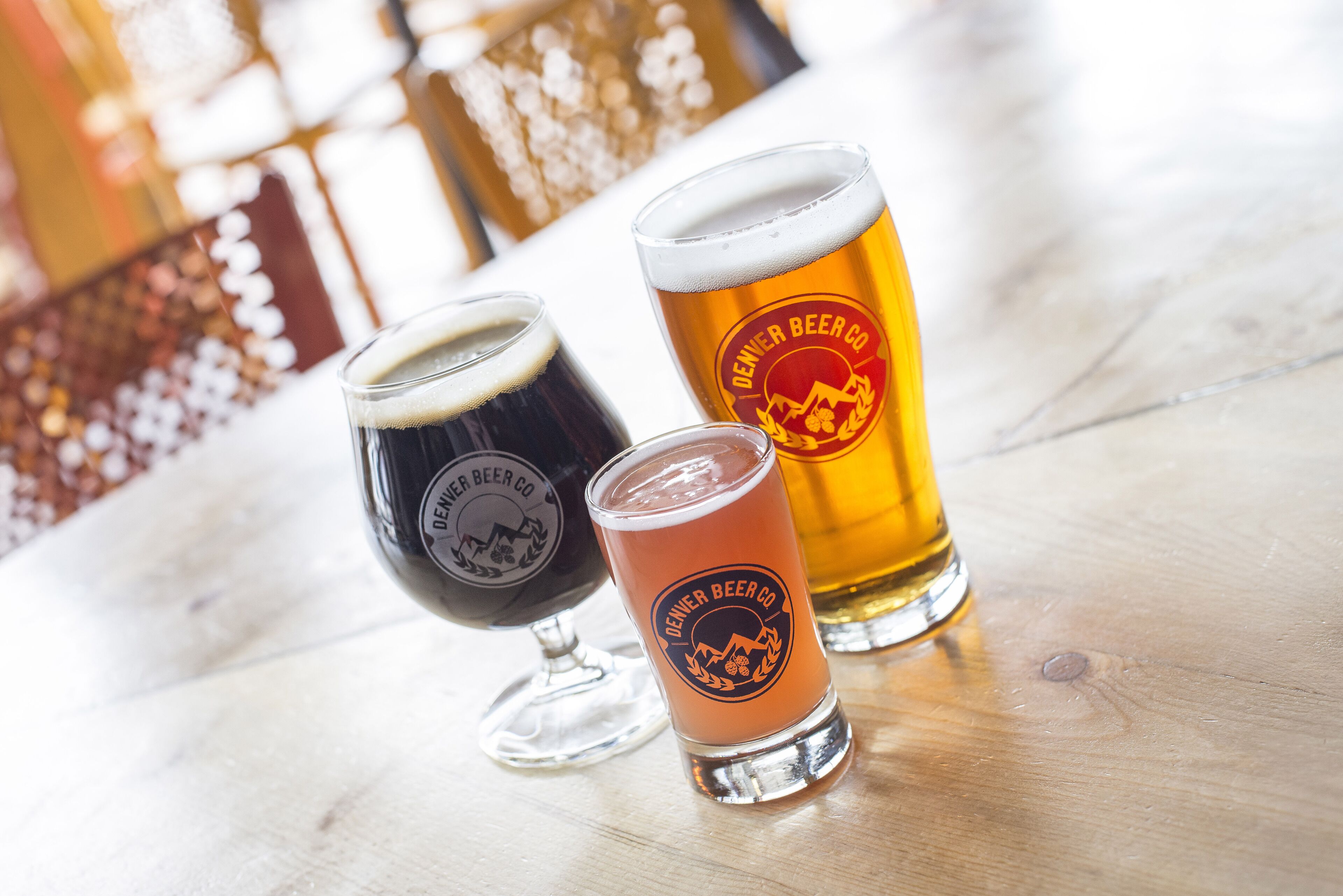 Three glasses of beer on a wooden surface.