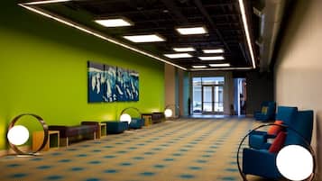 A spacious lobby with a patterned carpet, green walls, and a large abstract painting.
