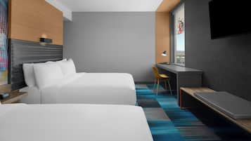 Une chambre d’hôtel avec deux lits, un bureau, une chaise, une télévision et une fenêtre donnant sur un beau paysage.