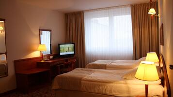 Une chambre d’hôtel avec deux lits, un bureau avec une télévision et des lampes.