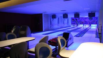 A bowling alley with multiple lanes, seating areas, and overhead televisions.