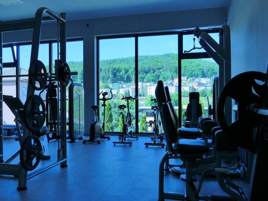 A gym with various exercise equipment, large windows, and a view of a town.