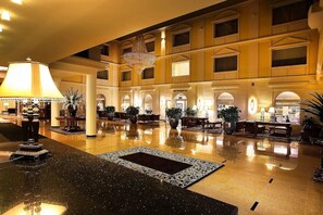 A spacious lobby with a polished floor, a large chandelier, and multiple seating areas.