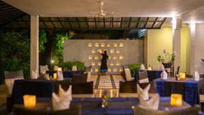 Un restaurante con terraza cubierta, mesas con velas y una persona de fondo.