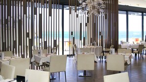Un restaurante con mesas dispuestas para comer, una gran araña y vistas al océano.