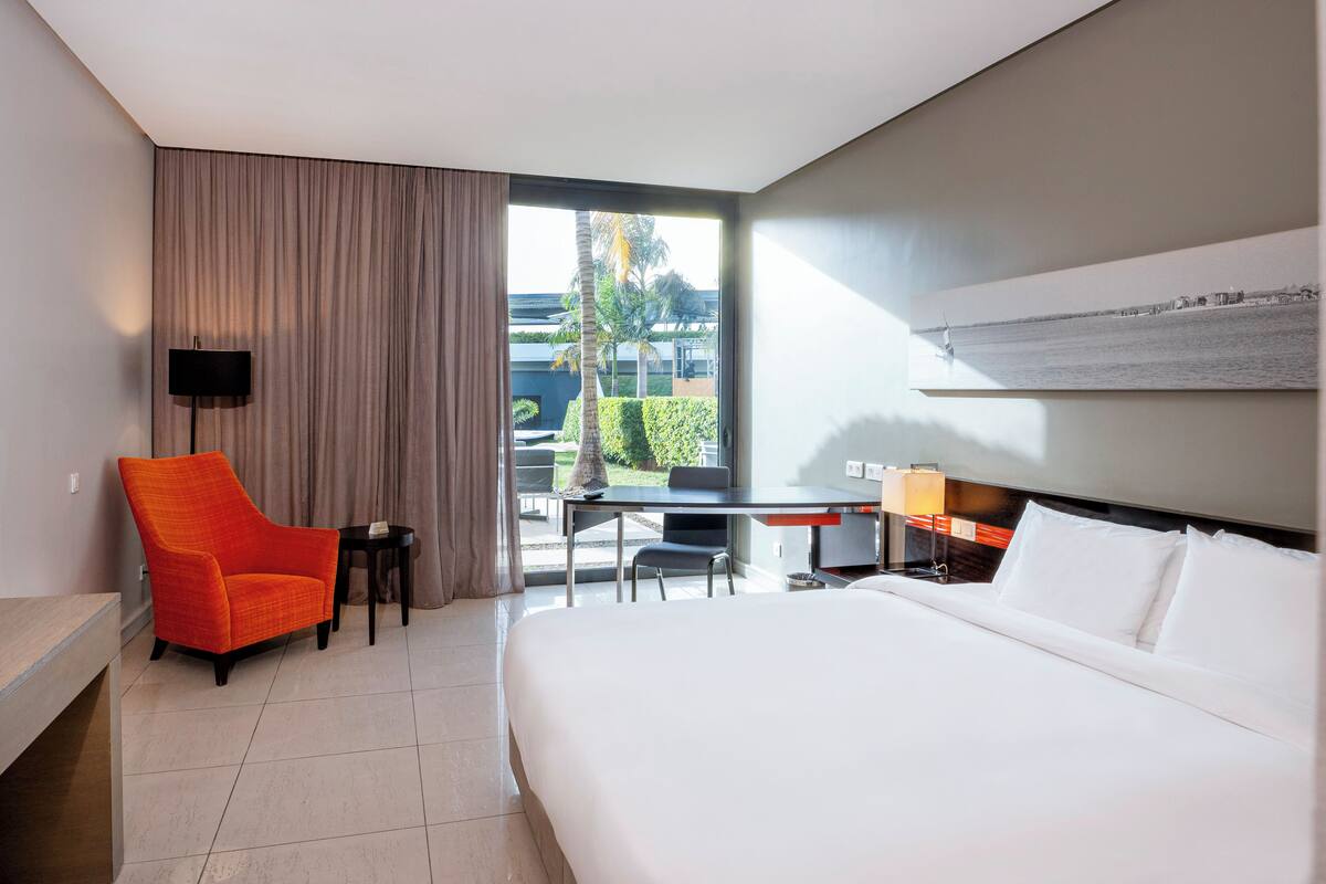Ein Hotelzimmer mit Bett, Schreibtisch, Stuhl und Blick ins Freie.