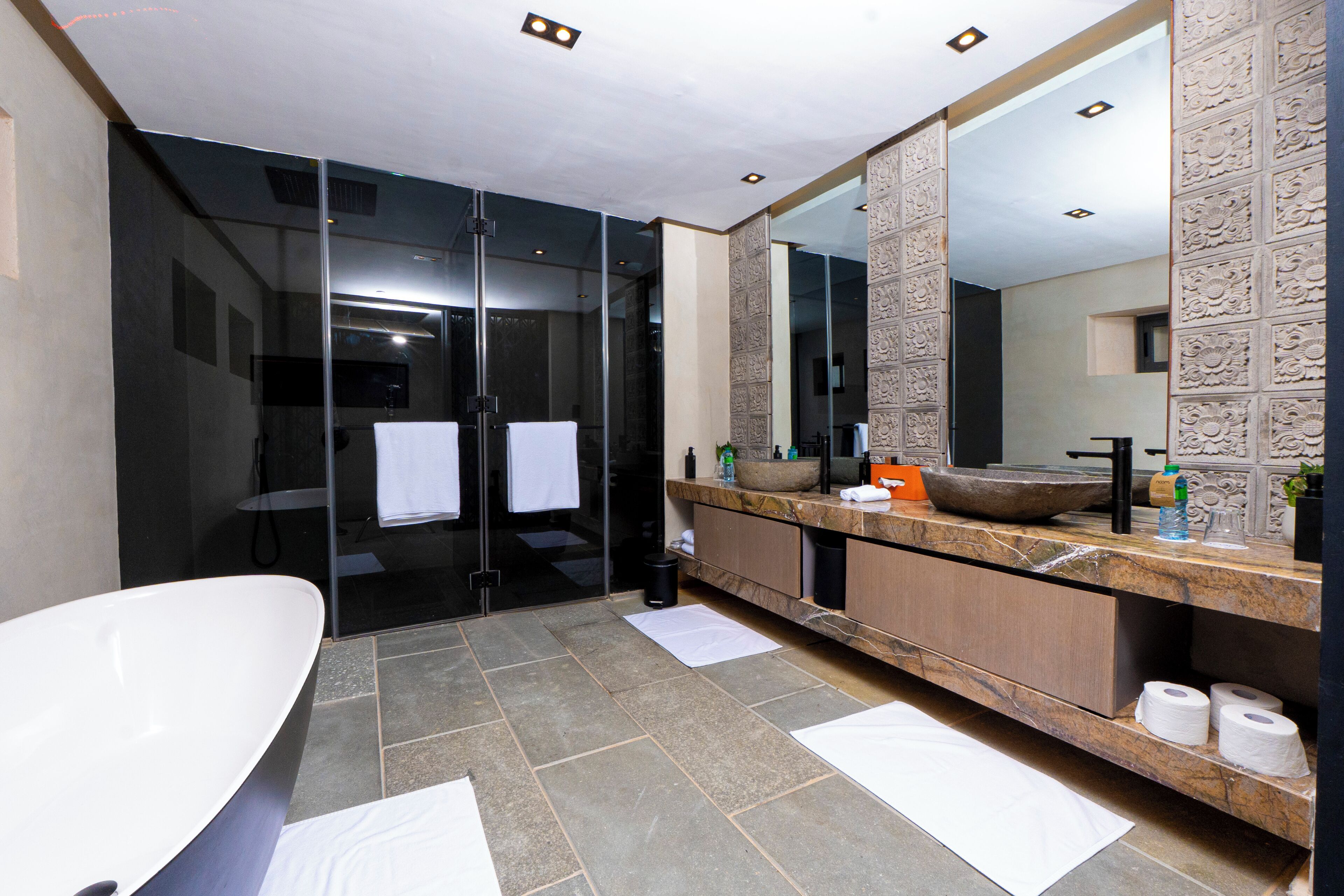 A modern bathroom with a freestanding bathtub, a large mirror, and a vanity with a sink and towel rack.