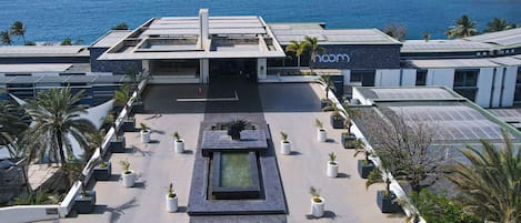 A hotel with a rooftop garden, a pool, and a view of the ocean.