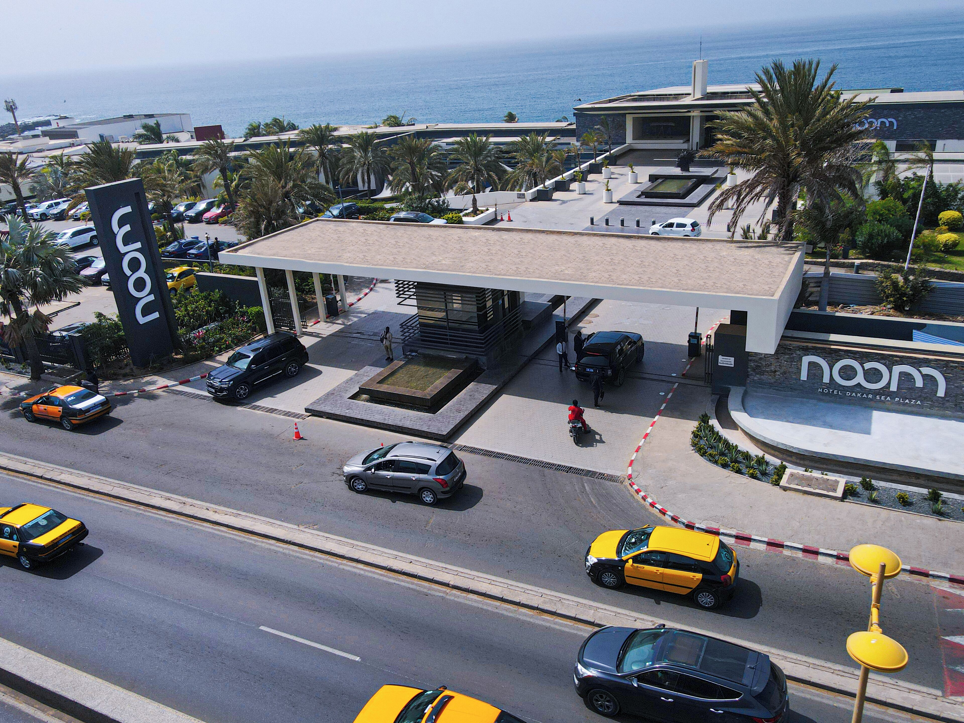 Un hotel moderno con una gasolinera, un estacionamiento y vistas al mar.