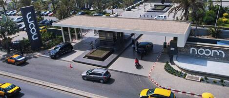 Un hotel moderno con una gasolinera, un estacionamiento y vistas al mar.