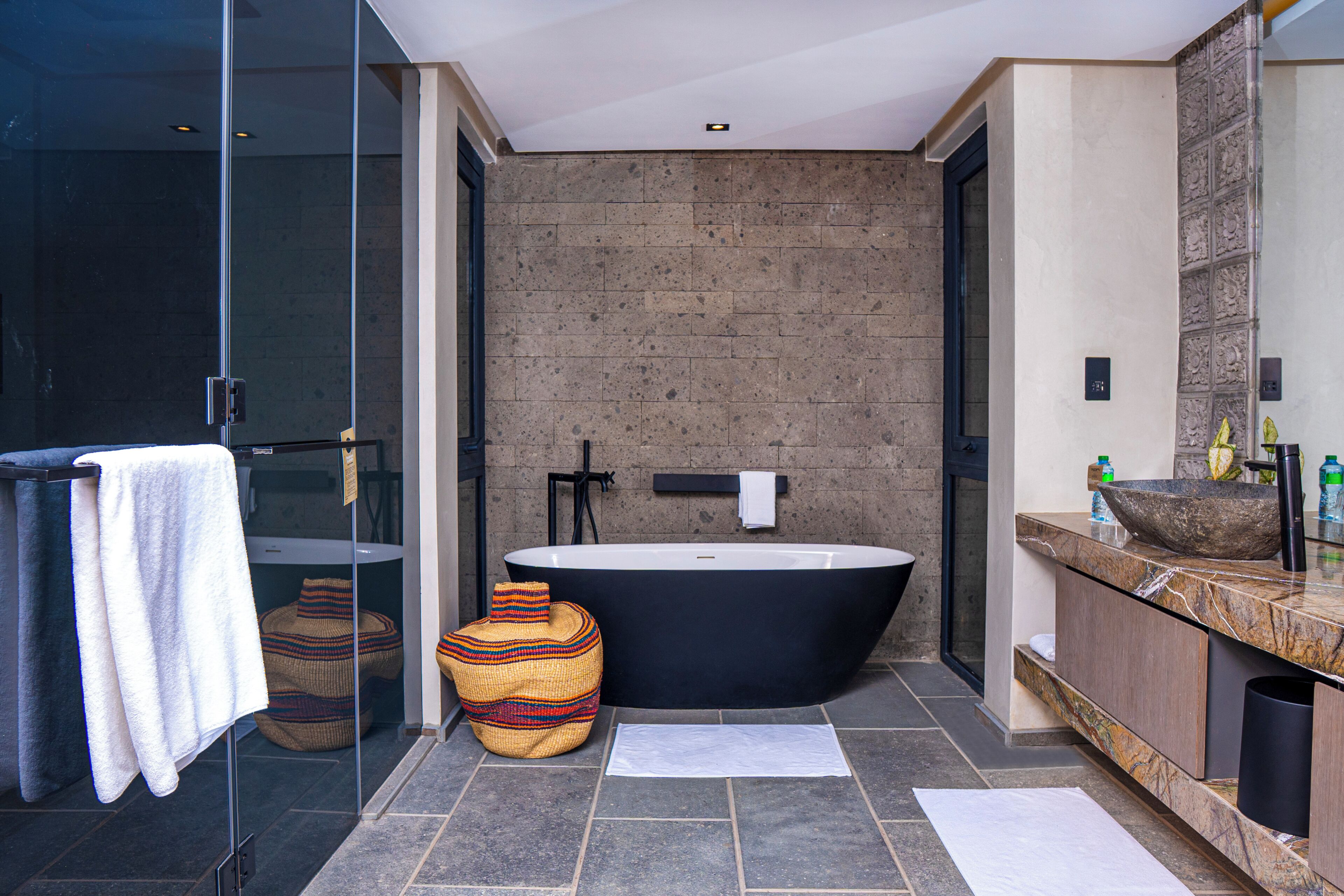 Un baño moderno con una bañera independiente, cabina de ducha de vidrio y tocador de mármol.