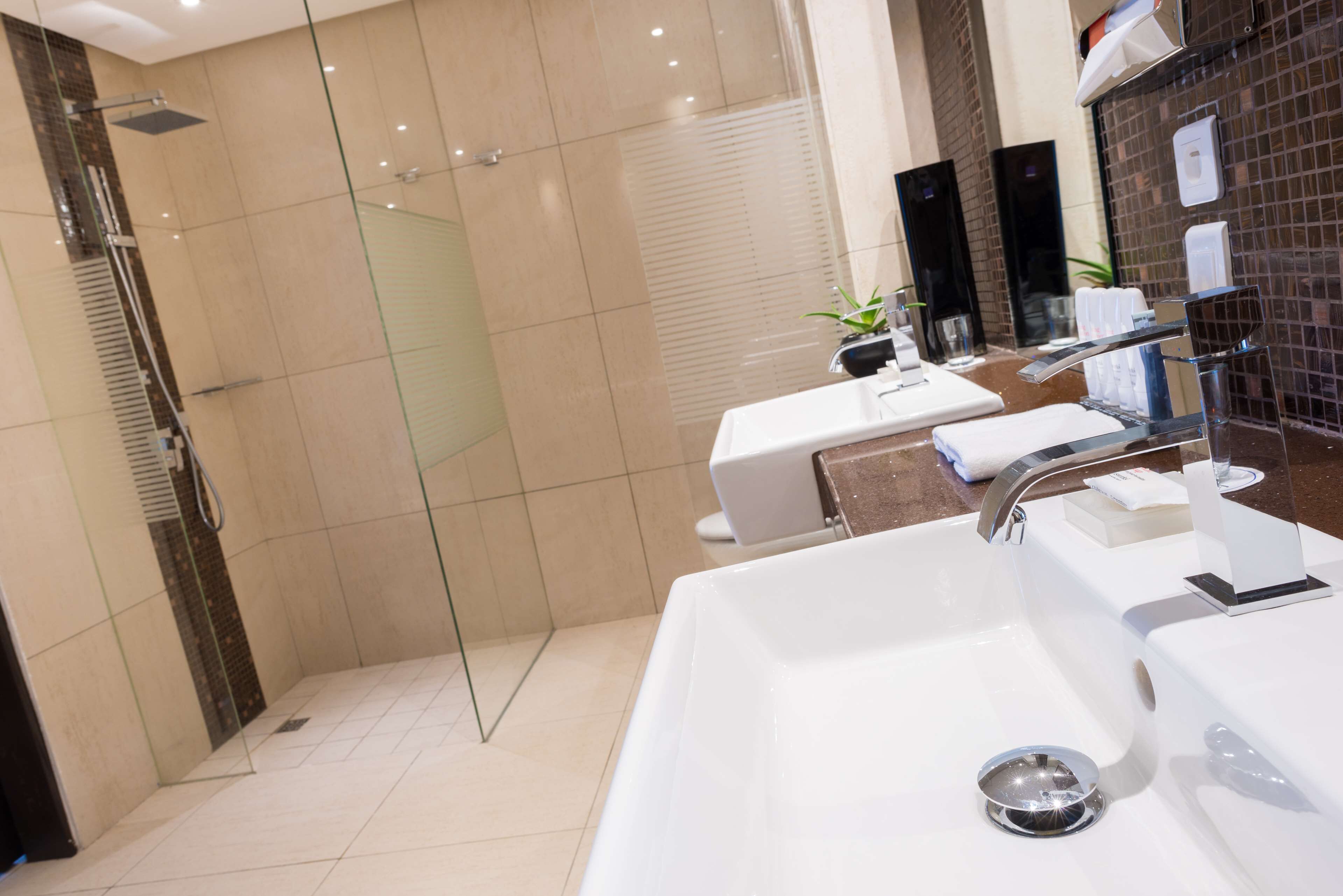 A modern bathroom with a glass-enclosed shower, a large white sink, and a mirror with a towel rack.