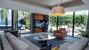 A modern living room with a large TV, comfortable seating, and a view of the outdoors.