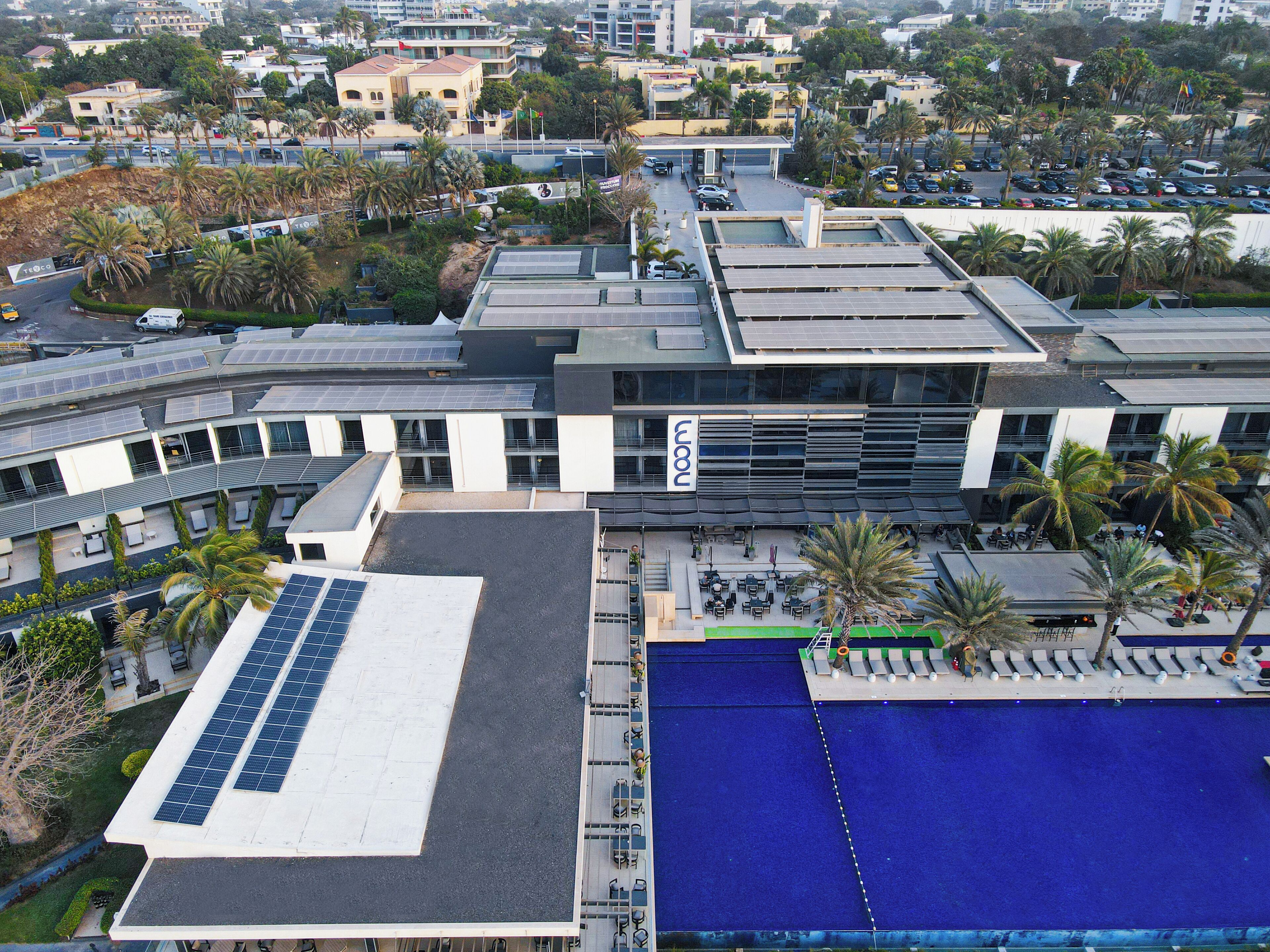 A modern building with solar panels, a swimming pool, and outdoor seating.