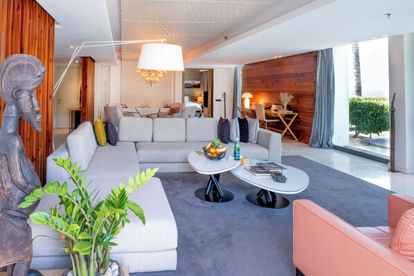 Una sala de estar moderna con un sofá modular, una mesa de centro redonda y un comedor con una mesa y sillas de madera.
