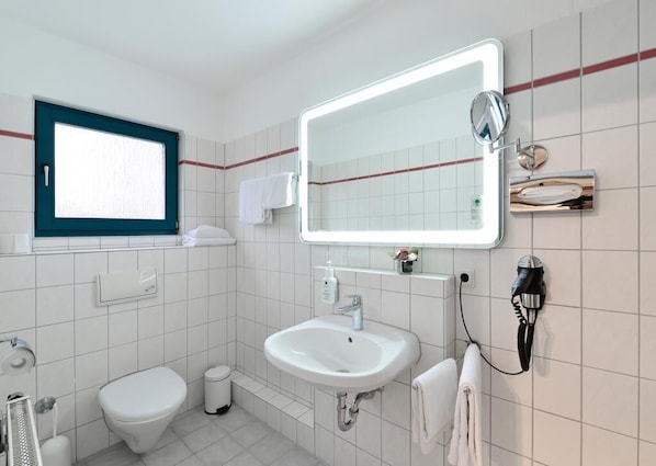 Un baño con inodoro, lavamanos y espejo.