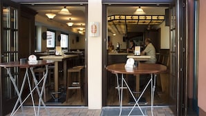 An entrance with two tables and chairs outside a restaurant. - Hotel Hansen (Bergisch Gladbach)