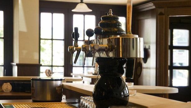 A coffee machine in a well-lit room with large windows and a wooden ceiling. - Hotel Hansen (Bergisch Gladbach)