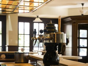 Une machine à café dans une pièce bien éclairée, dotée de grandes fenêtres et d’un plafond en bois.