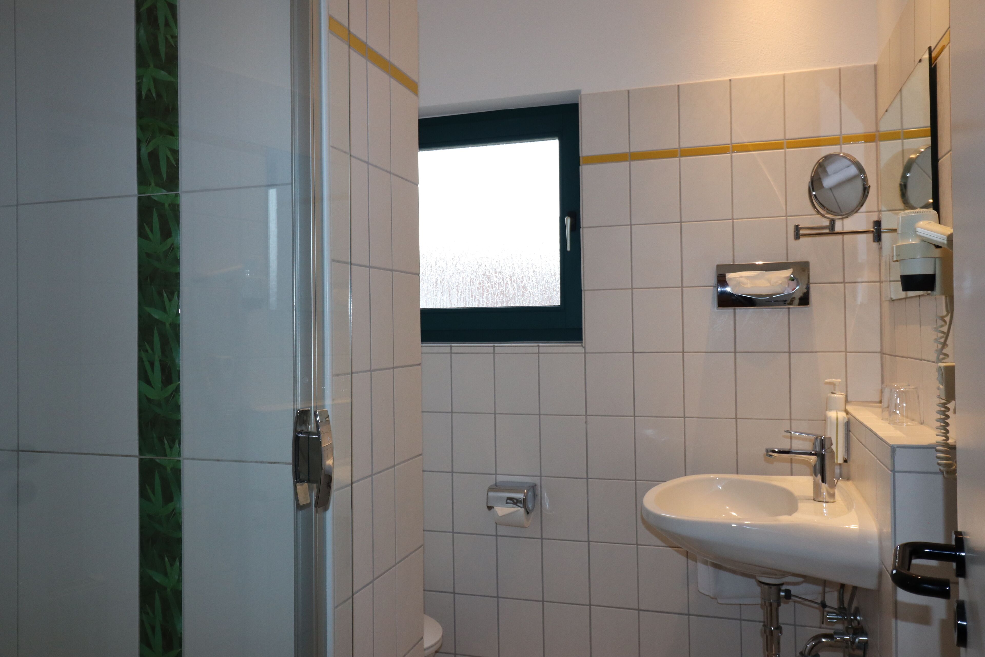 A bathroom with a toilet, sink, mirror, and a small window.