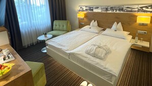 Een hotelkamer met twee bedden, een bureau met stoel, een klein tafeltje en een televisie.