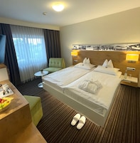 A hotel room with two beds, a desk with a chair, a small table, and a TV.