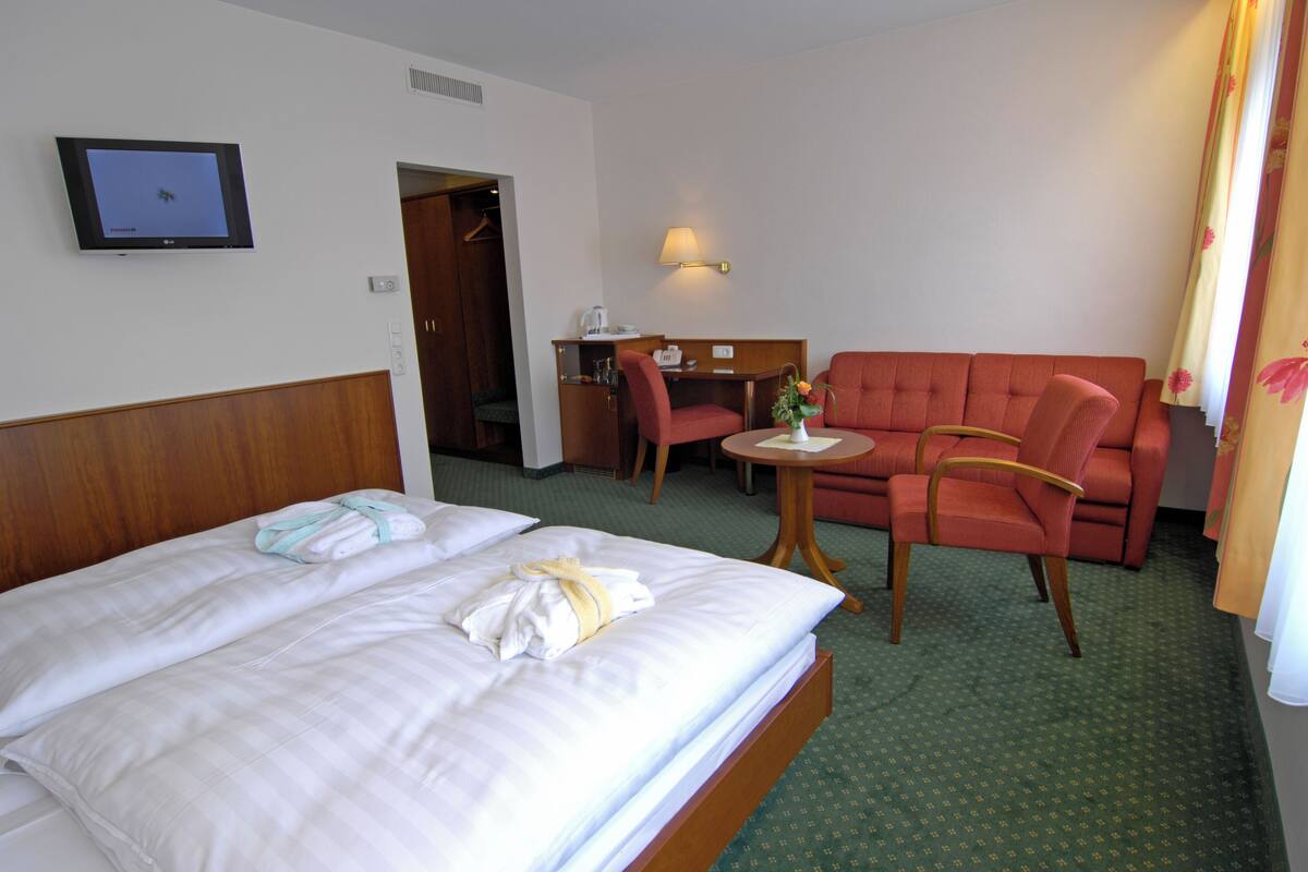 Une chambre d’hôtel avec un lit, un bureau, une chaise et un canapé.