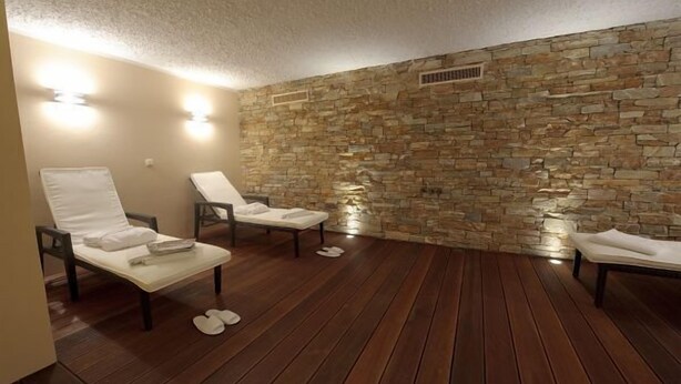 Een wellnessruimte met stenen muren, houten vloeren en twee comfortabele fauteuils.