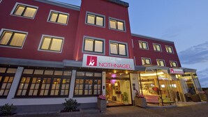 Een hotelgebouw met meerdere verdiepingen, grote ramen en een bord met de tekst Nothnagel Hotel.