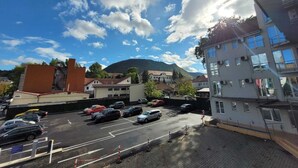 Um estacionamento com vários carros, edifícios e uma montanha ao fundo.
