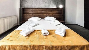 Quarto de hotel com cama, cabeceira, radiador e janela.