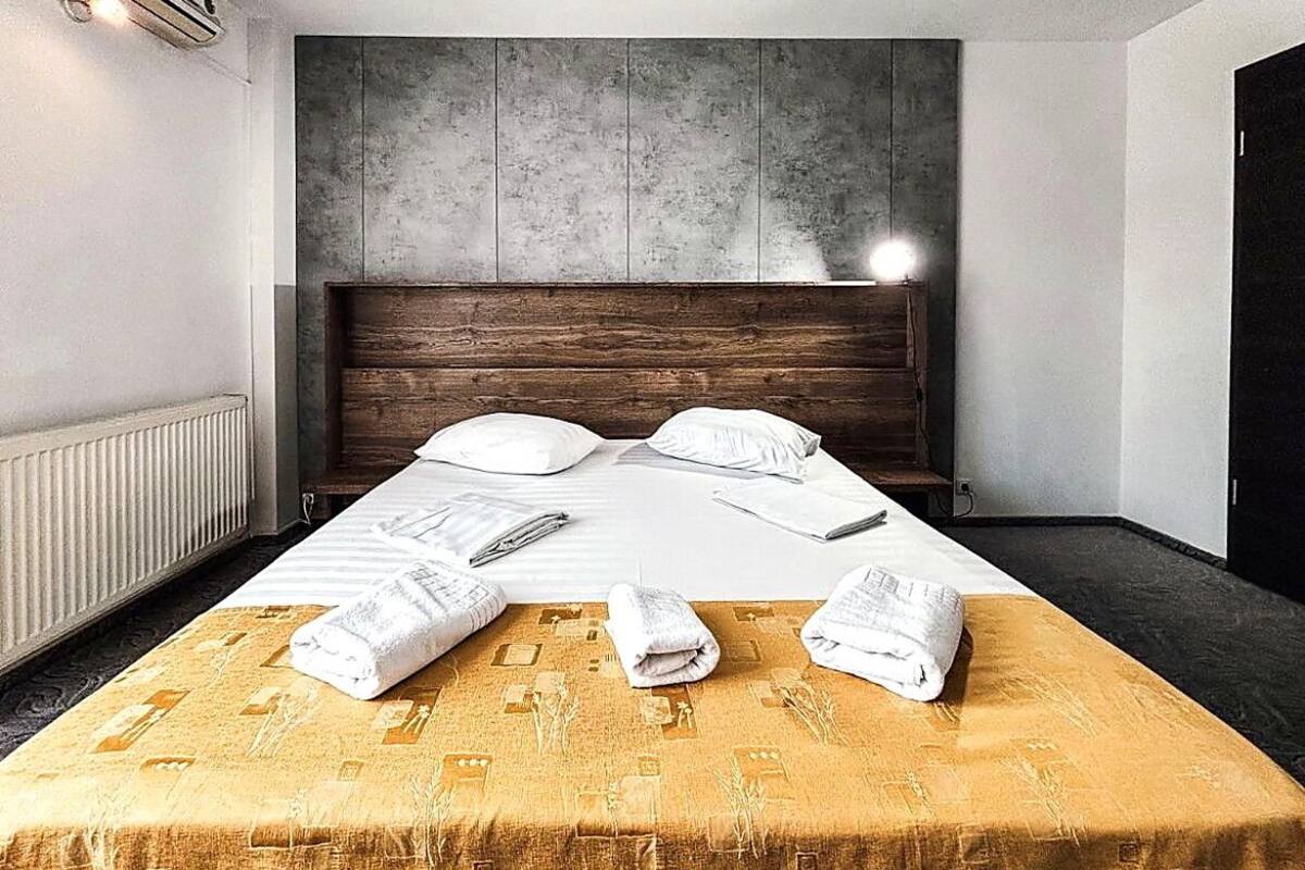 Ein Hotelzimmer mit Bett, Kopfteil, Heizkörper und Fenster.