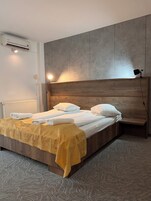 Una habitación de hotel moderna con una cama de madera, un cabecero, una mesita de noche y una lámpara.
