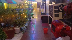 A hallway with potted plants, a Christmas tree, and a red fire hydrant. - Hotel Sidhartha (Agra)