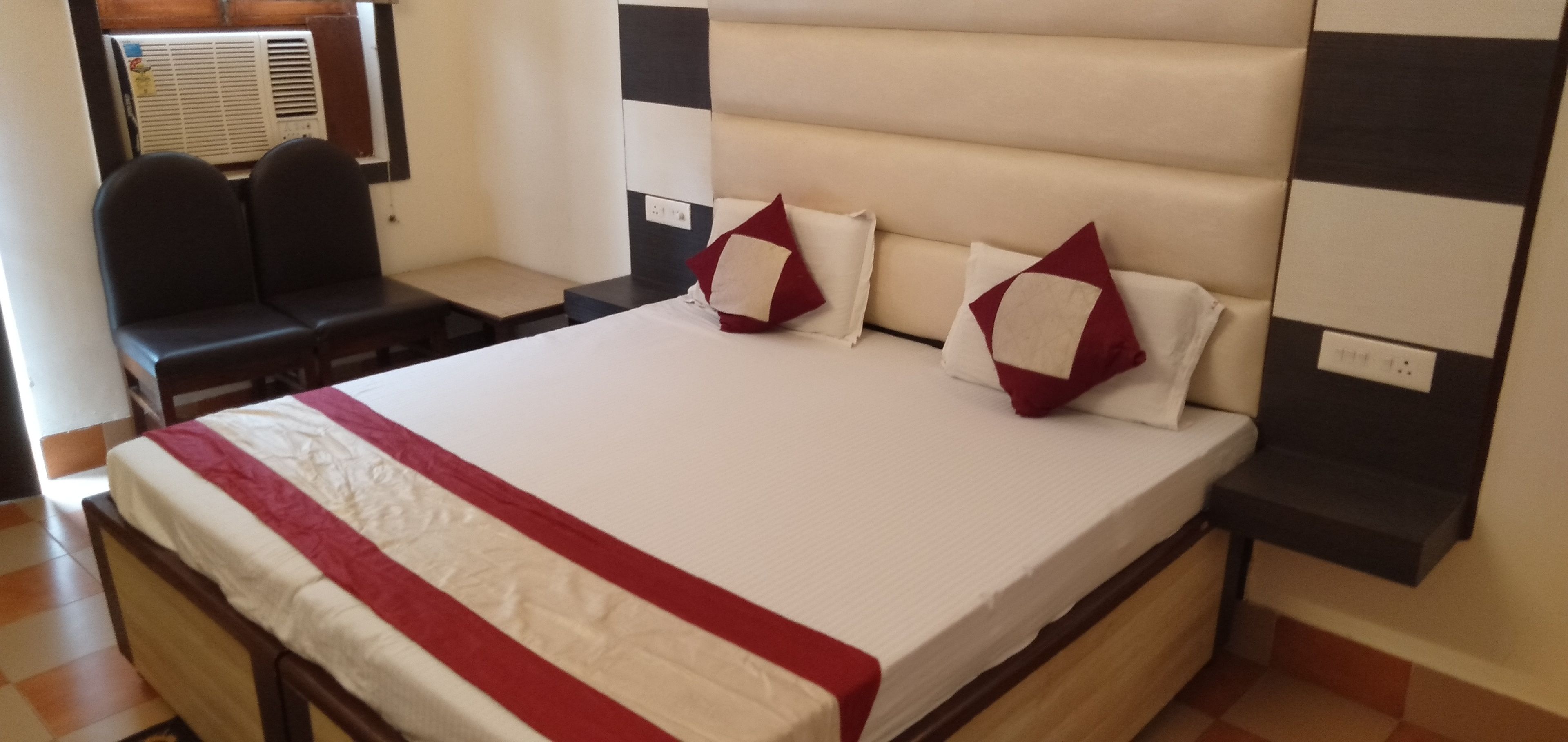A neatly made bed with a red and white bedspread, two pillows, and a headboard with a black and white pattern.