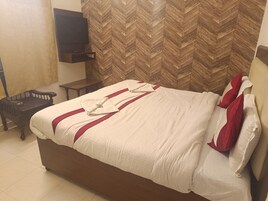 Habitación de hotel con una cama grande, cabecero de madera, televisor de pantalla plana montado en la pared y un revestimiento de madera con motivo de espiga.