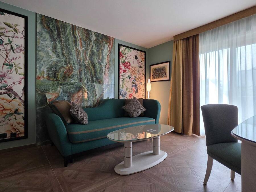 A living room with a green sofa, a glass coffee table, and a chair.