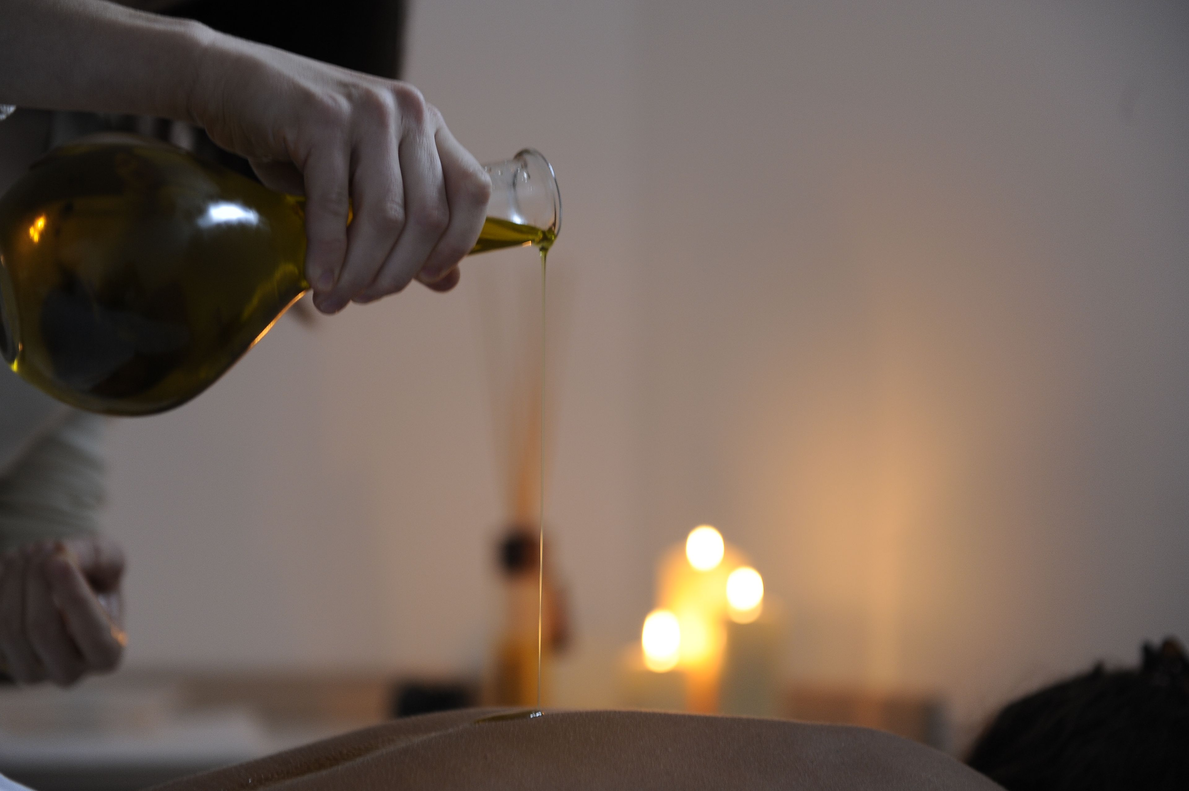 Iemand giet olijfolie uit een fles.