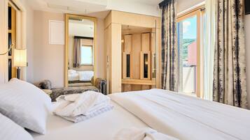 Habitación de hotel con una cama grande, una zona de estar con una silla, un armario de madera y un espejo amplio.