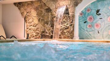 Un área de spa con una cascada, pared de piedra y decoración de rosales.