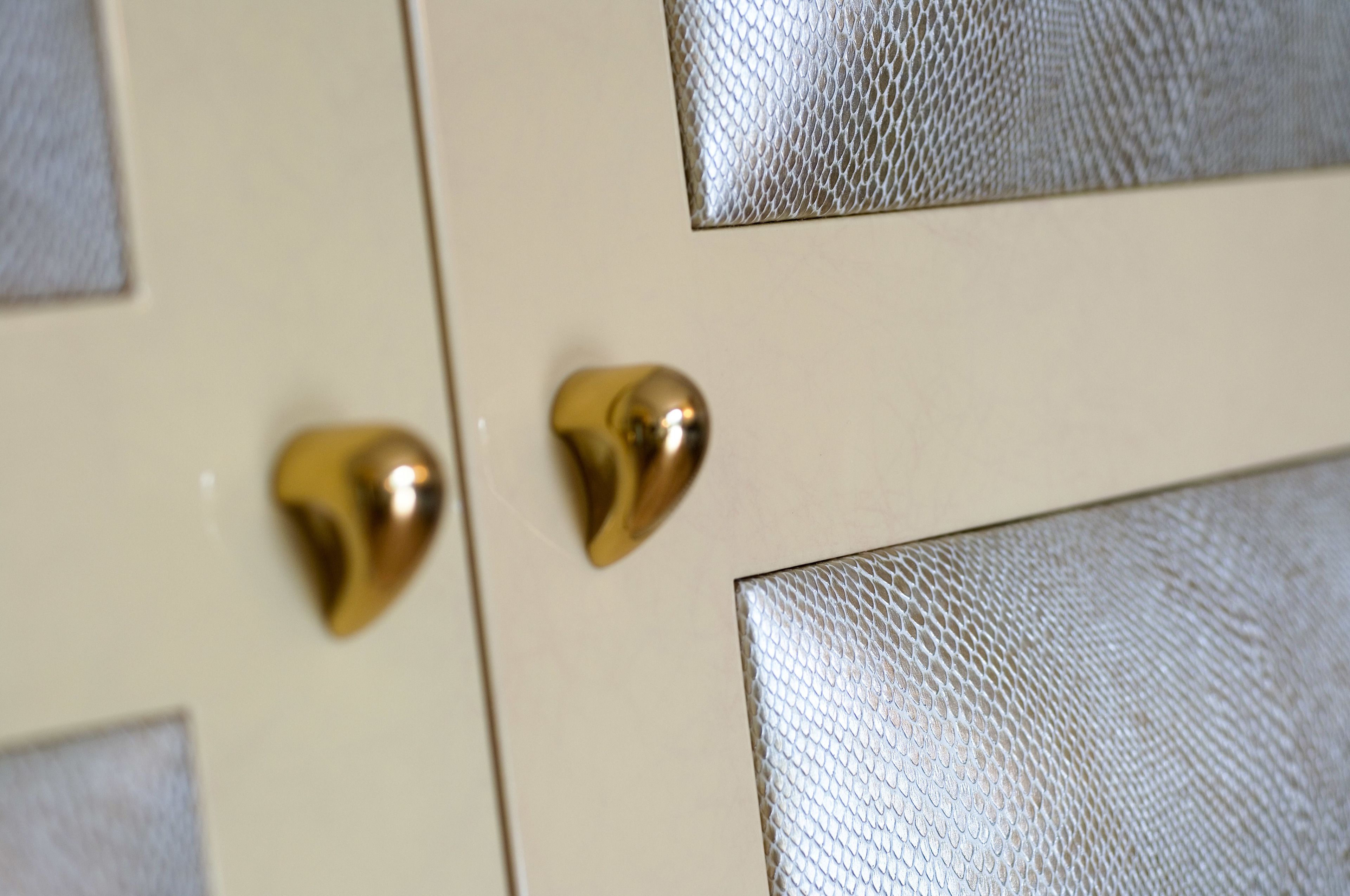 A close-up of a door with a textured panel and two brass handles.