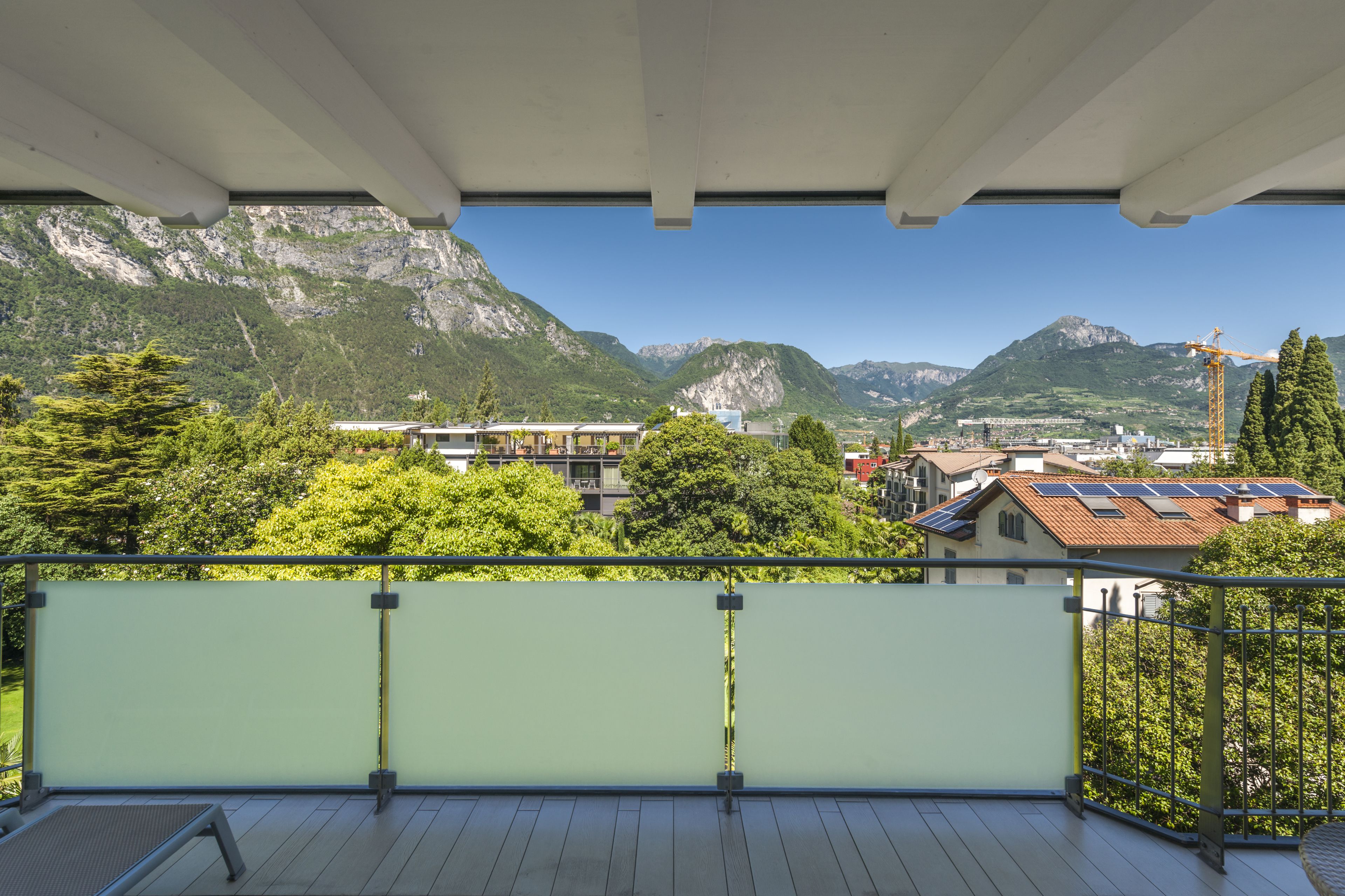 A balcony with a view of mountains and a construction crane in the distance.