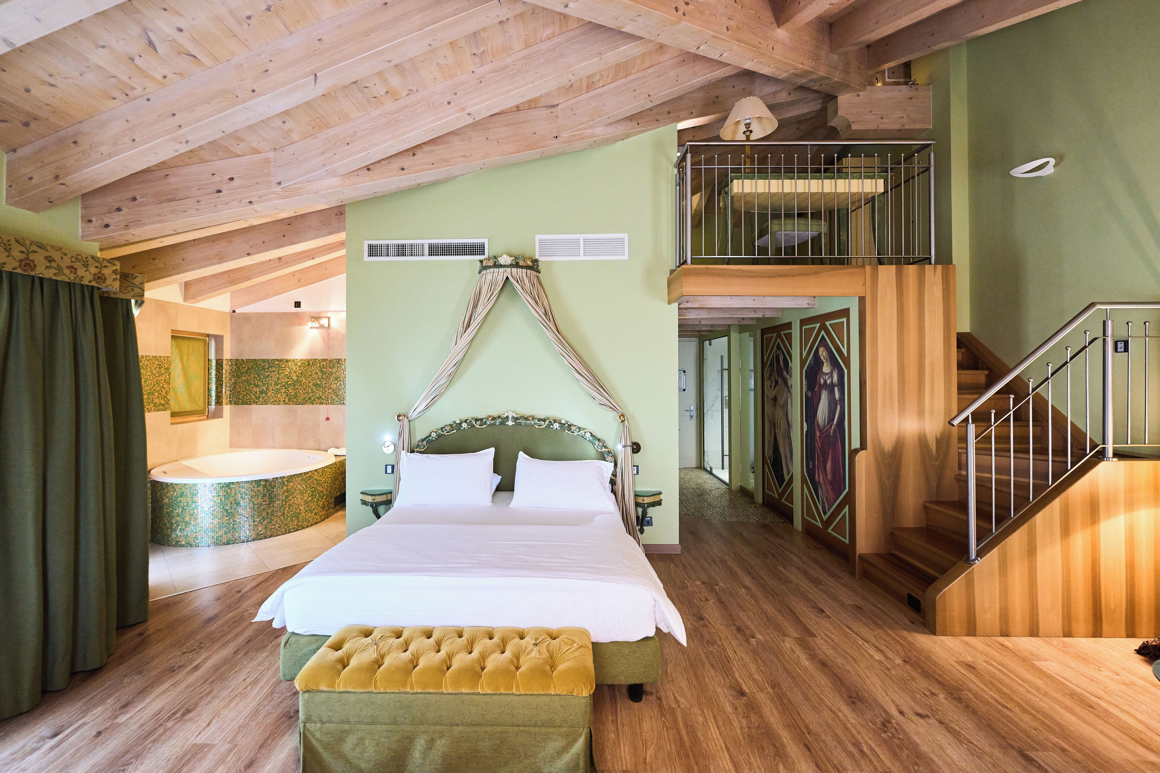 A spacious bedroom with a large bed, a wooden staircase, and a balcony.