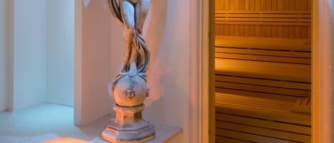 Un'area benessere con una statua in marmo, una panca riscaldata e una scala illuminata.