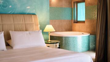 A hotel room with a bed, a nightstand, a lamp, and a bathtub.