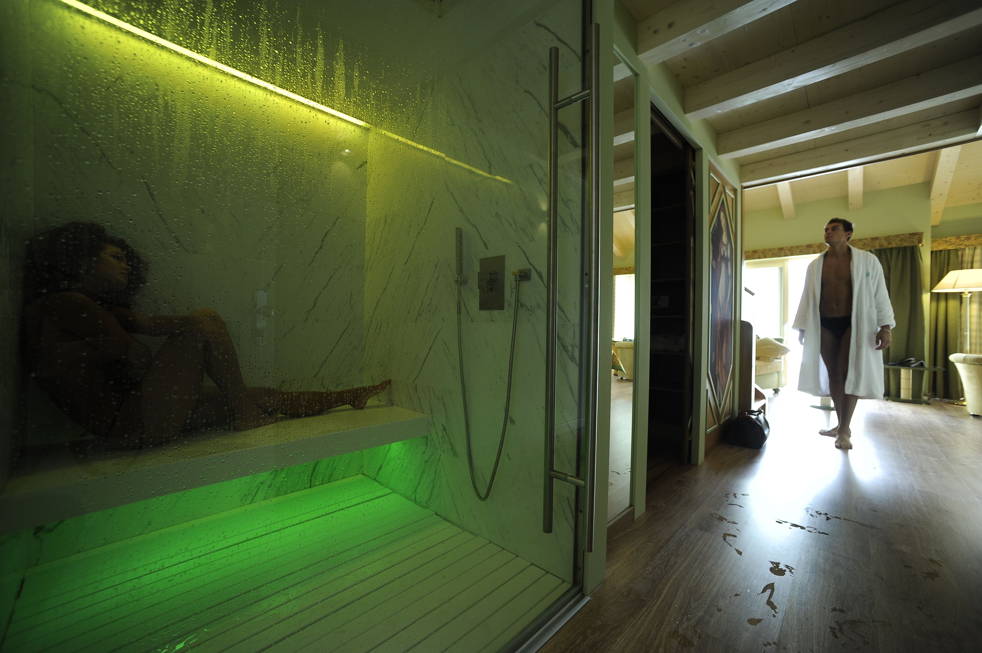 A spa area with a glass-enclosed hot tub, a wooden bench, and a shower area.